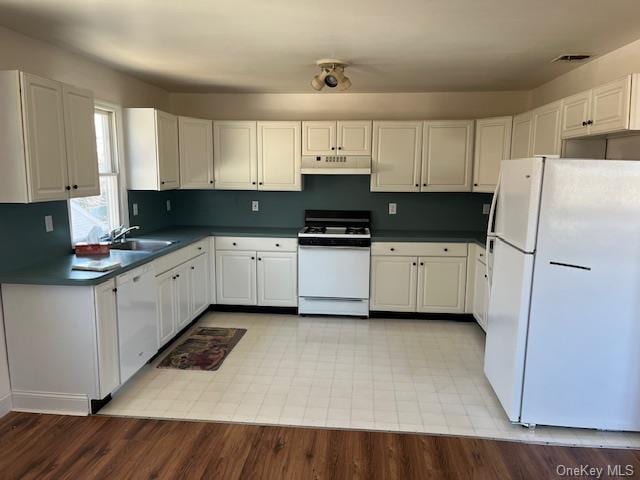 kitchen featuring dark countertops, white cabinetry, a sink, white appliances, and under cabinet range hood