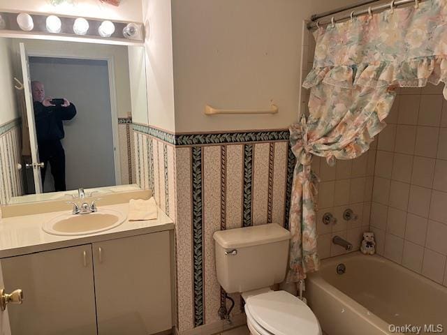 bathroom with toilet, a wainscoted wall, bathtub / shower combination, vanity, and tile walls