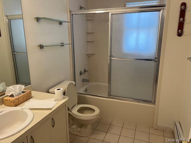 bathroom with tile patterned flooring, toilet, a baseboard heating unit, shower / bath combination with glass door, and vanity