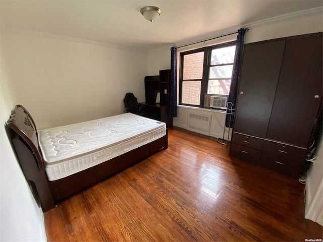 bedroom with hardwood / wood-style floors, radiator heating unit, and cooling unit