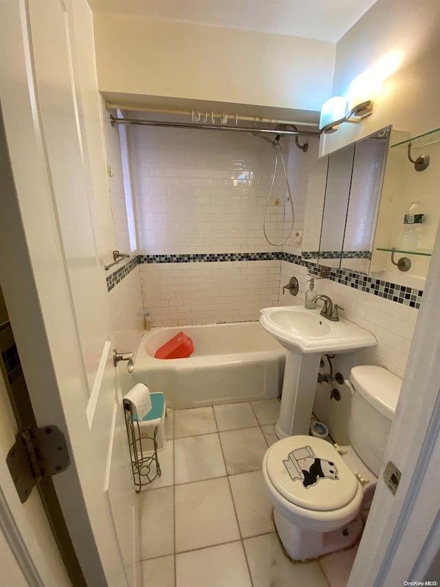 bathroom with tile patterned flooring, tiled shower / bath combo, toilet, and tile walls