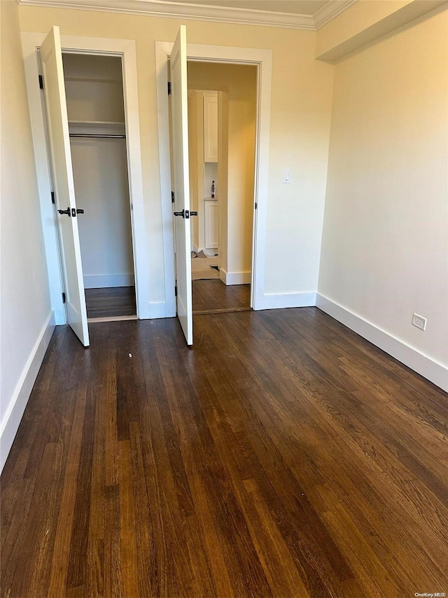 unfurnished bedroom featuring a closet, dark hardwood / wood-style floors, and ornamental molding