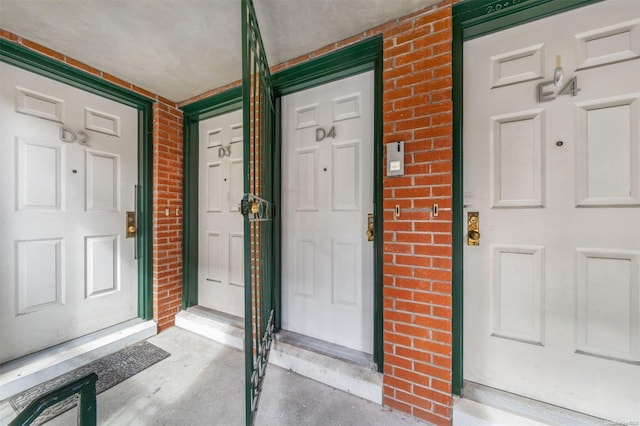 doorway to property featuring brick siding and covered porch