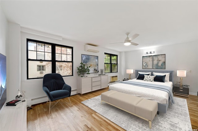 bedroom featuring a baseboard heating unit, light wood-style floors, ceiling fan, and a wall mounted AC