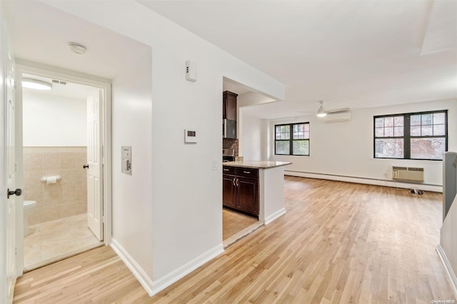 kitchen featuring dark brown cabinets, ceiling fan, open floor plan, a wall mounted air conditioner, and light wood-style floors