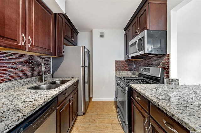 kitchen with visible vents, a sink, tasteful backsplash, stainless steel appliances, and light stone countertops