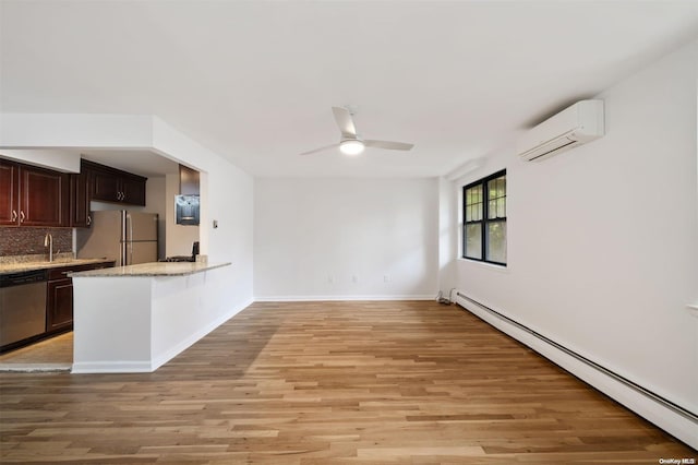 kitchen with a wall mounted AC, freestanding refrigerator, stainless steel dishwasher, light wood-type flooring, and baseboard heating