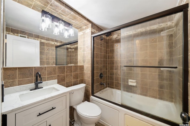 bathroom featuring vanity, bath / shower combo with glass door, tile walls, toilet, and tasteful backsplash