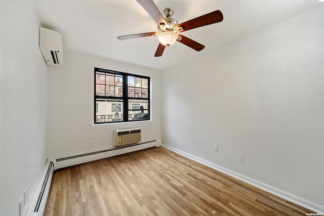 spare room with baseboards, baseboard heating, an AC wall unit, and light wood-style flooring