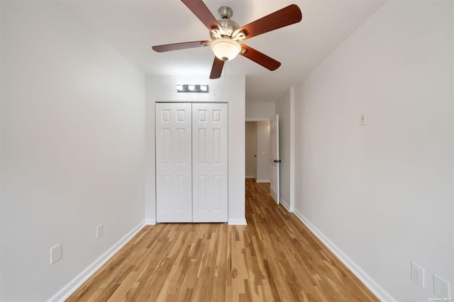 unfurnished bedroom with a closet, baseboards, light wood-style flooring, and a ceiling fan