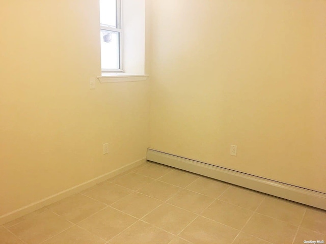 tiled spare room featuring baseboard heating