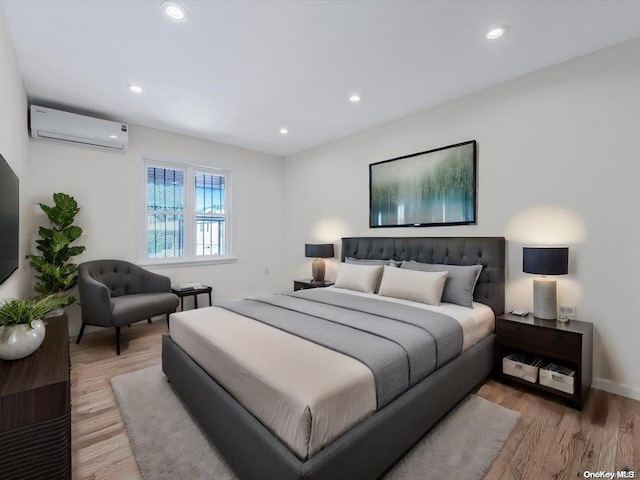 bedroom with a wall mounted AC and light hardwood / wood-style floors