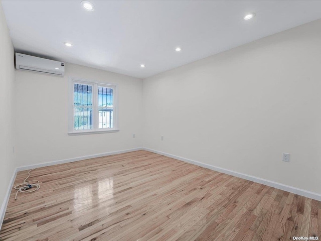 empty room with light hardwood / wood-style flooring and a wall unit AC