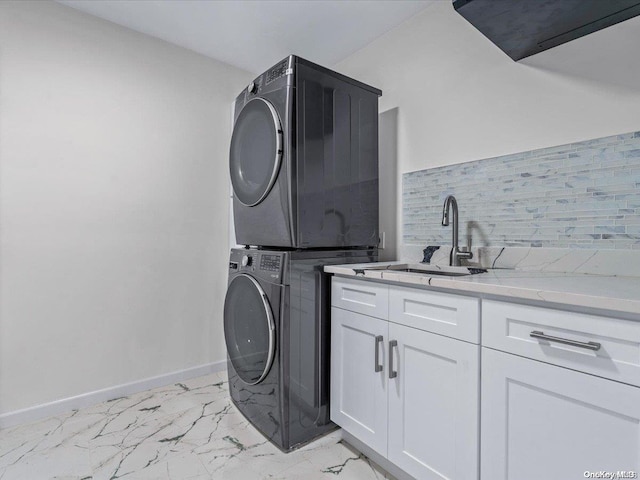 washroom featuring stacked washer / dryer, sink, and cabinets