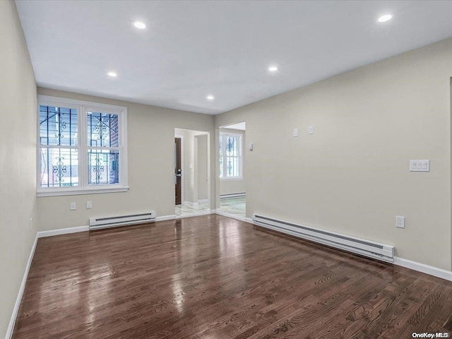 spare room featuring dark wood-type flooring and a baseboard radiator