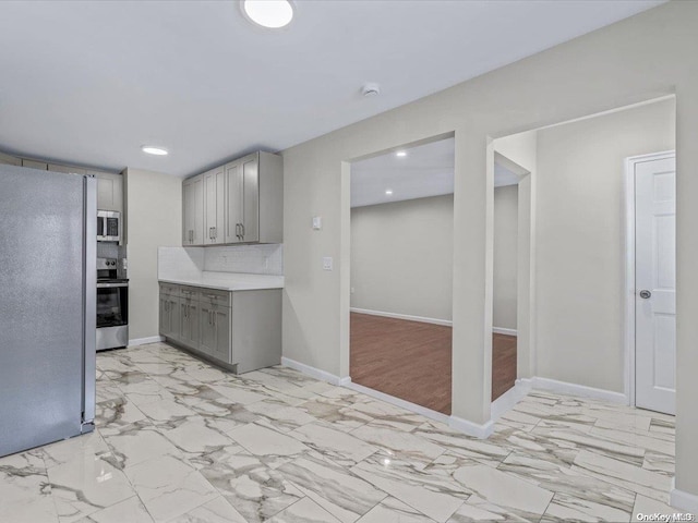 kitchen featuring tasteful backsplash, gray cabinets, stainless steel appliances, and light wood-type flooring