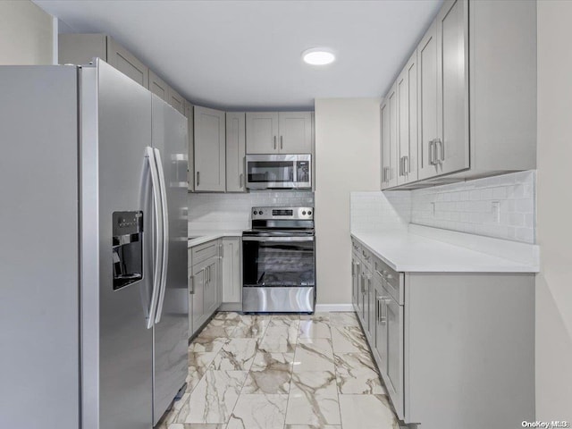 kitchen featuring gray cabinetry, stainless steel appliances, and tasteful backsplash