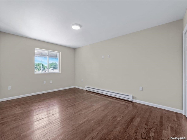 unfurnished room featuring dark wood-type flooring and a baseboard heating unit