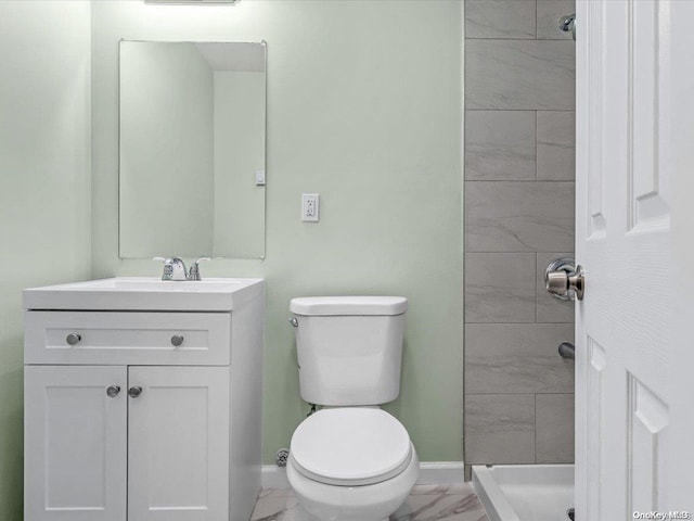 bathroom with a tile shower, vanity, and toilet