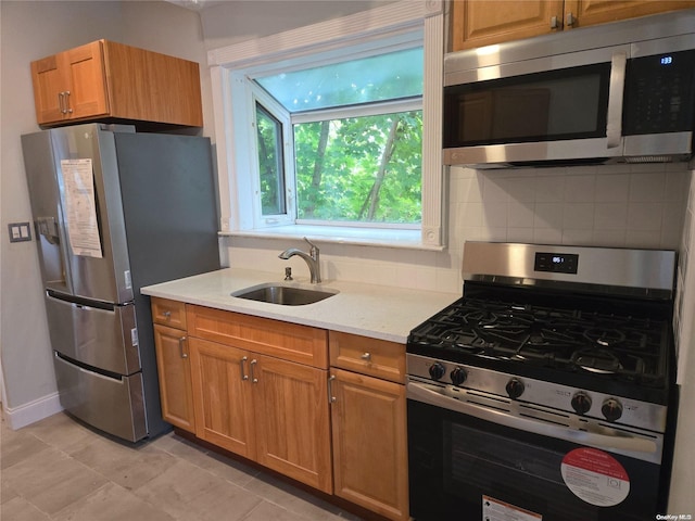 kitchen featuring backsplash, stainless steel appliances, light stone counters, and sink