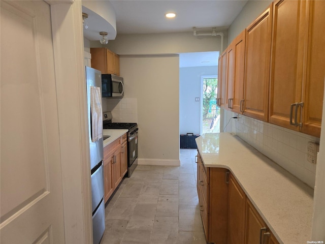 kitchen with backsplash, light stone countertops, and appliances with stainless steel finishes