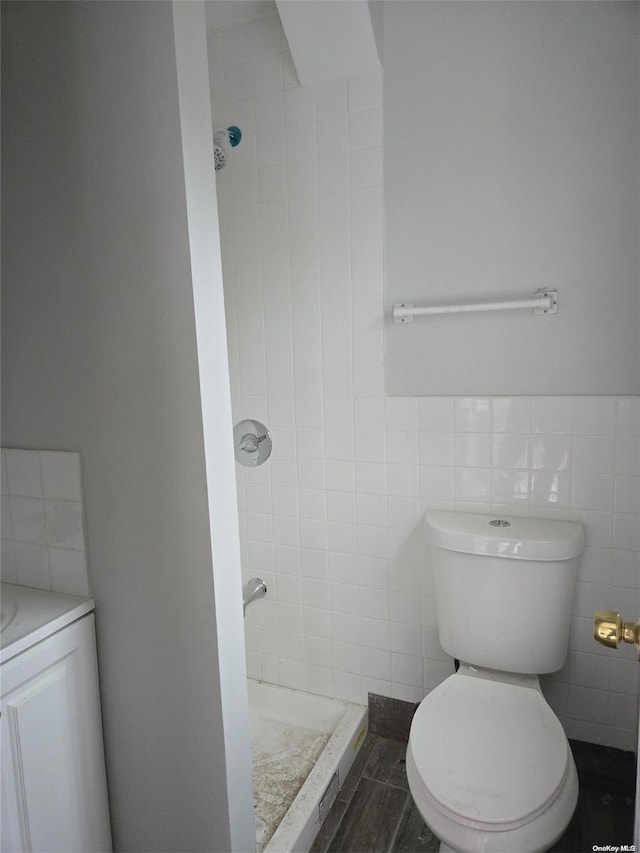 bathroom featuring tile patterned floors, toilet, tile walls, and a tile shower