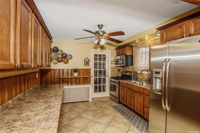 kitchen with appliances with stainless steel finishes, light tile patterned floors, ceiling fan, and sink