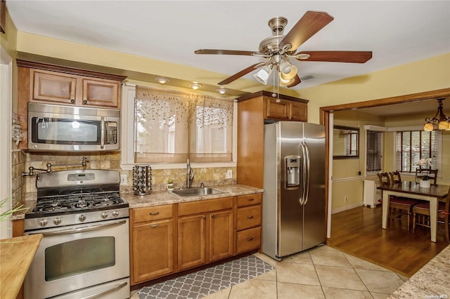 kitchen featuring decorative backsplash, light wood-type flooring, stainless steel appliances, ceiling fan, and sink