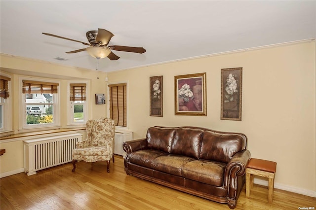 living room featuring light hardwood / wood-style flooring, radiator, ornamental molding, and ceiling fan