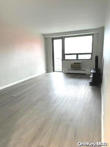 unfurnished living room with hardwood / wood-style flooring and an AC wall unit