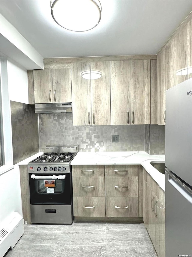 kitchen with backsplash, light stone countertops, baseboard heating, and appliances with stainless steel finishes