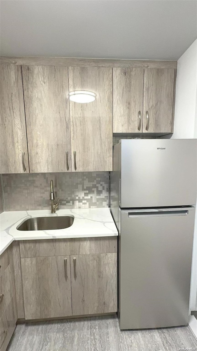 kitchen featuring stainless steel fridge, sink, and light hardwood / wood-style flooring