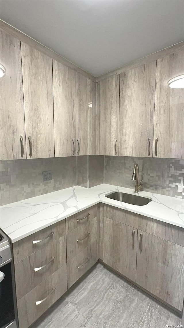 kitchen with electric stove, light stone countertops, and sink