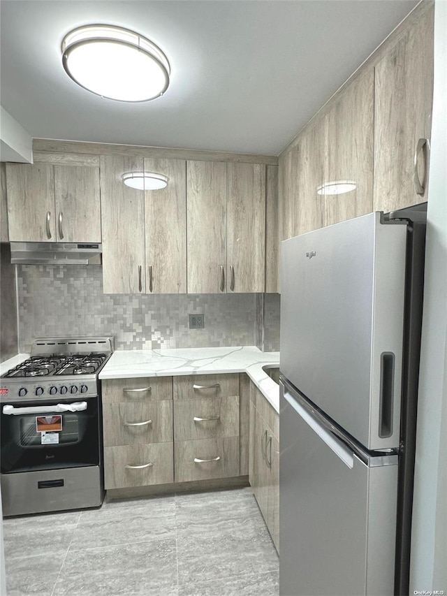 kitchen featuring light brown cabinets, light stone countertops, light tile patterned floors, tasteful backsplash, and stainless steel appliances