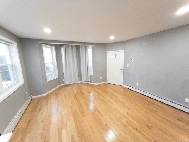 unfurnished room featuring light hardwood / wood-style floors and a baseboard radiator