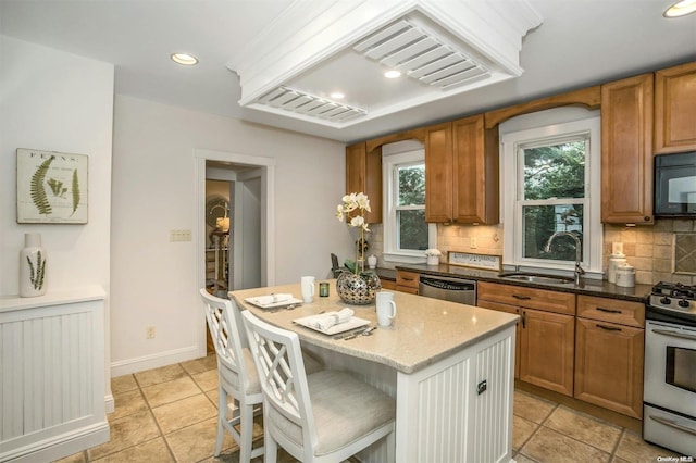 9 N Bayles Ave, Port Washington, NY 11050 - kitchen with stainless steel dishwasher, dark stone counters, gas range oven, sink, and a center island