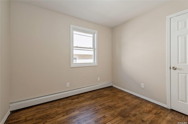 empty room featuring dark wood-type flooring and a baseboard radiator