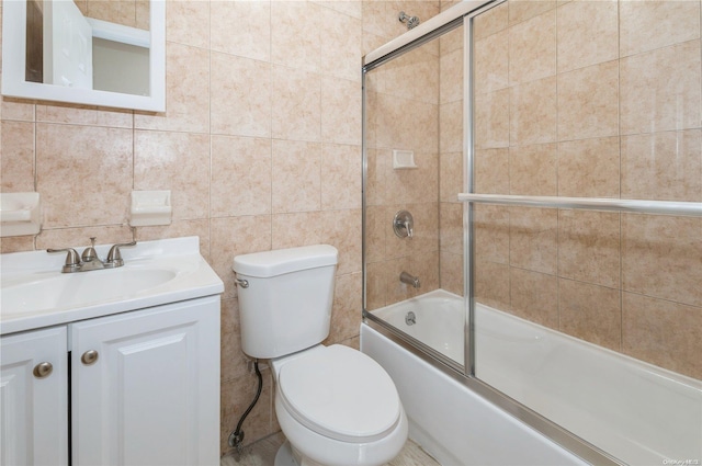 full bathroom featuring shower / bath combination with glass door, vanity, toilet, and tile walls