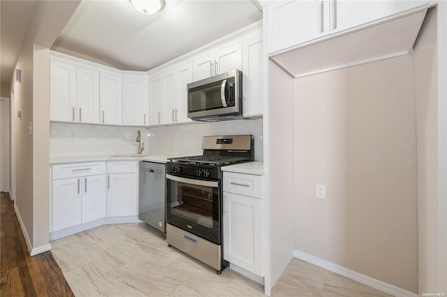 kitchen featuring decorative backsplash, white cabinetry, sink, and appliances with stainless steel finishes