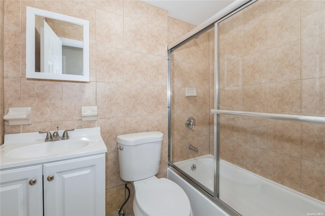 full bathroom with vanity, bath / shower combo with glass door, tile walls, and toilet