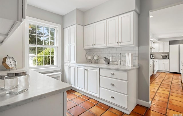 kitchen with white cabinetry, light tile patterned floors, and tasteful backsplash