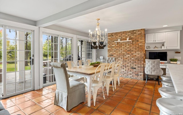 dining room with tile patterned floors, brick wall, and an inviting chandelier