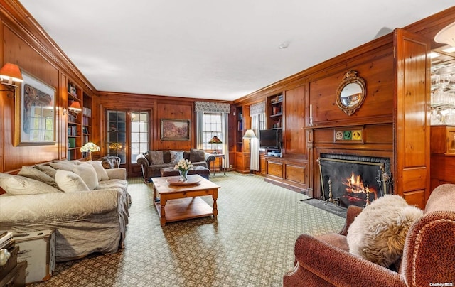 living room with built in shelves, wooden walls, and crown molding