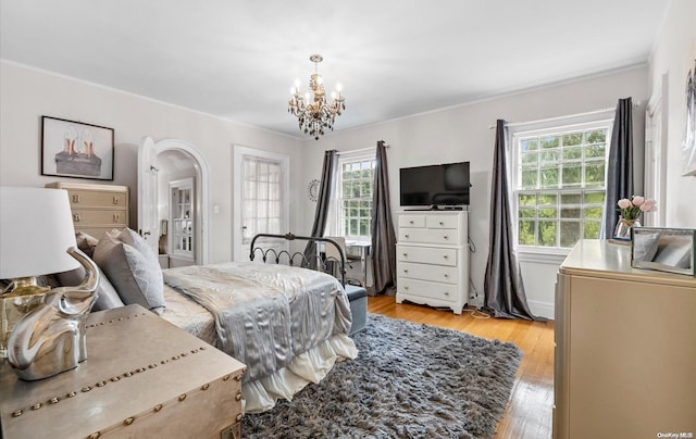 bedroom with a notable chandelier, ornamental molding, and light hardwood / wood-style flooring