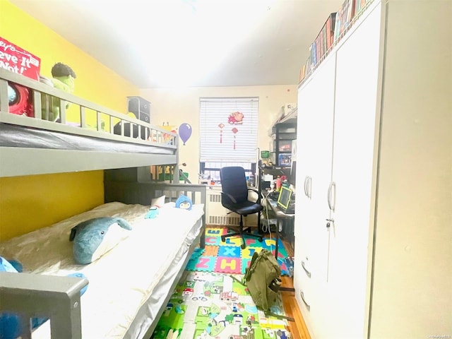 bedroom with light hardwood / wood-style floors, radiator heating unit, and a closet