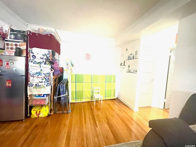 kitchen with wood-type flooring, ornamental molding, and stainless steel refrigerator