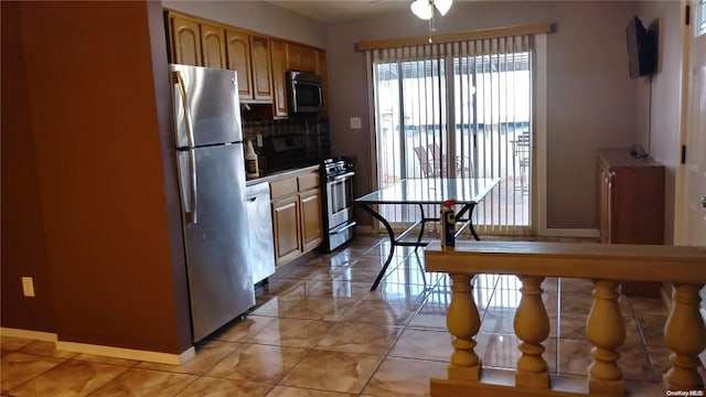 159-29 92nd St, Howard Beach, NY 11414 - kitchen featuring appliances with stainless steel finishes, baseboards, decorative backsplash, a ceiling fan, and brown cabinets