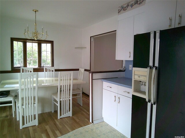 kitchen featuring refrigerator with ice dispenser, white cabinetry, hanging light fixtures, an inviting chandelier, and light wood-type flooring