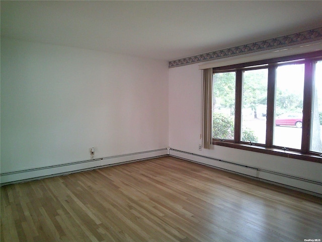 empty room featuring a baseboard radiator and light wood-type flooring