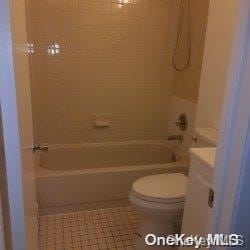 full bathroom with tile patterned flooring, vanity, tiled shower / bath combo, and toilet